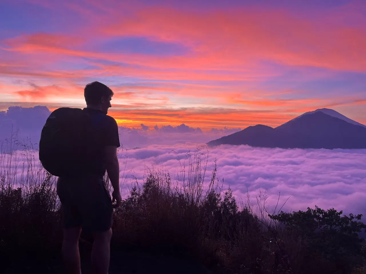 A hiker in silhouette above a sea of cloud at sunrise, Mount Batur area