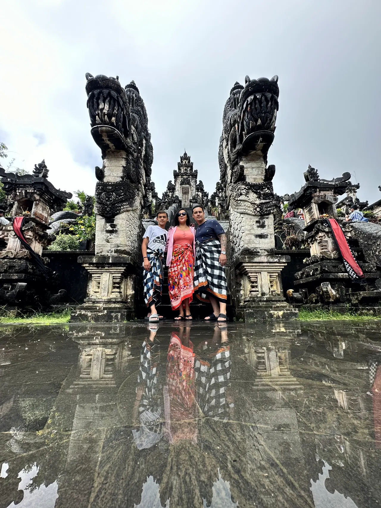 A group in traditional sarongs beneath the carved gate at Lempuyang