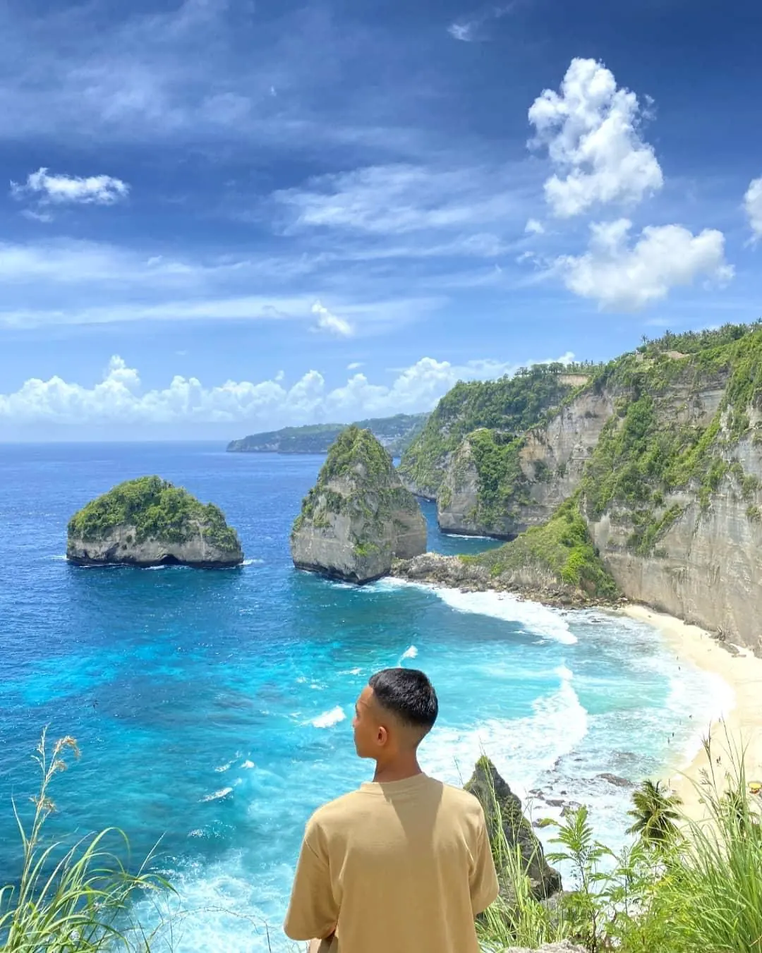A visitor looking out at the Kelingking cliff and beach on Nusa Penida