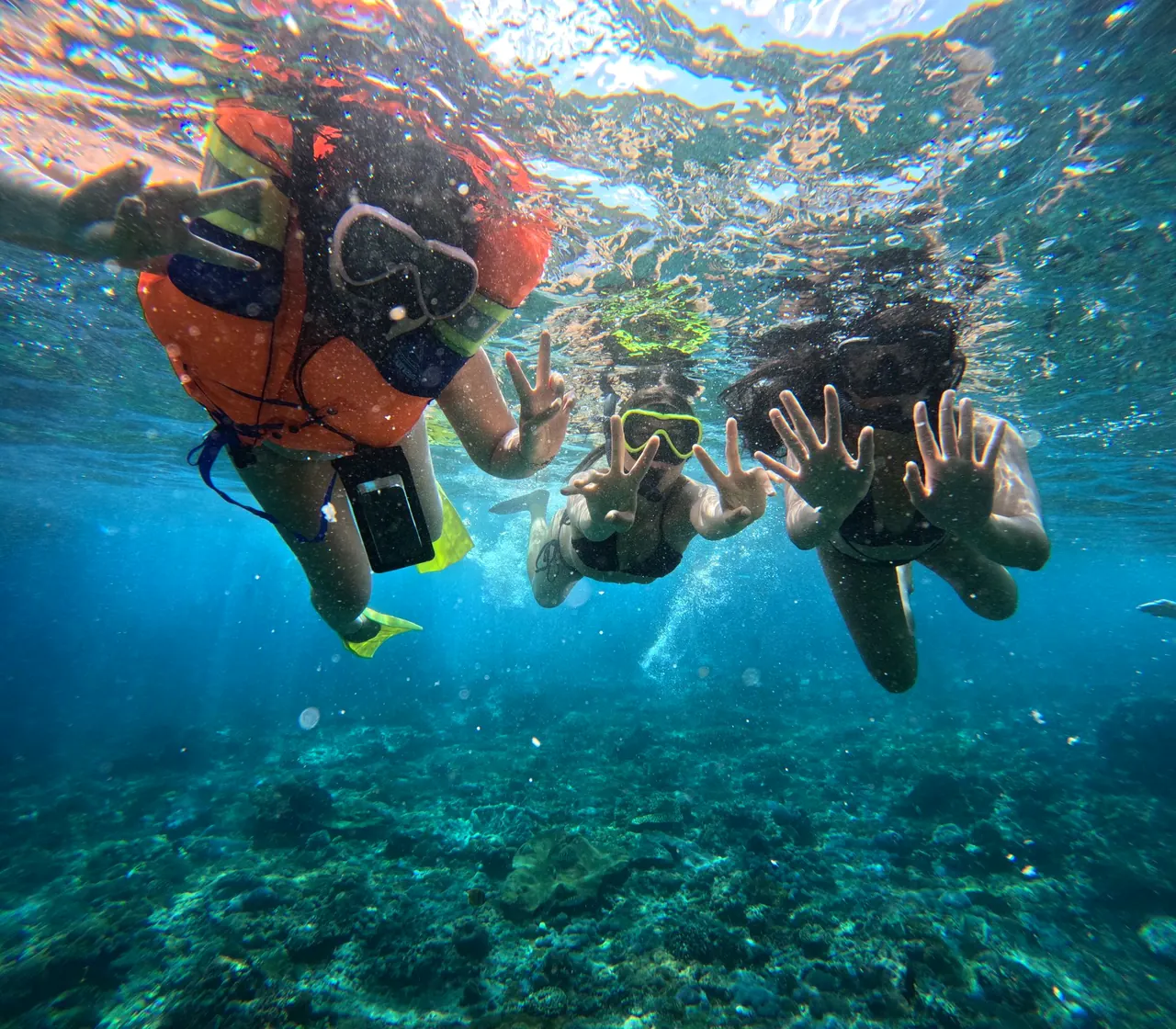 Two snorkellers swimming down toward the reef and smiling at the camera