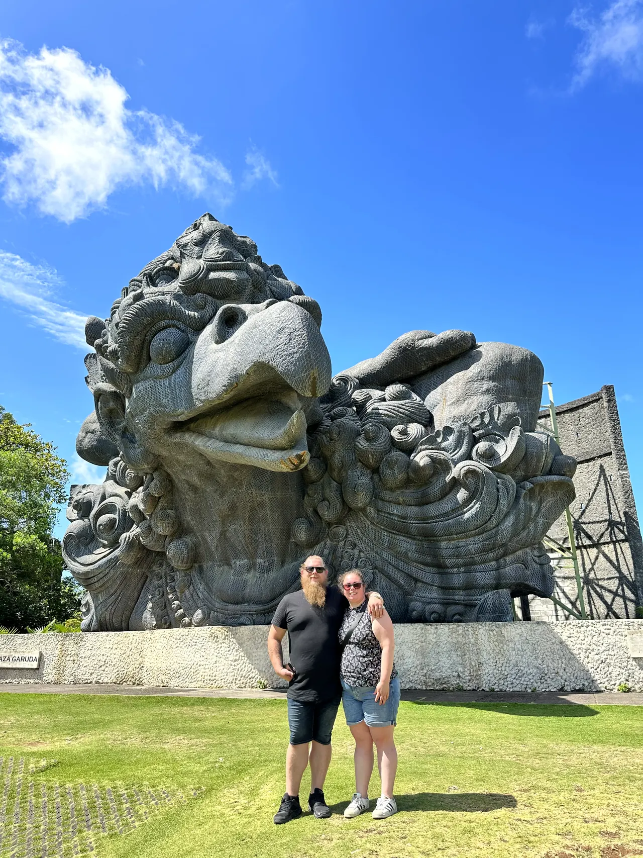 A couple standing before the huge Garuda head sculpture at GWK